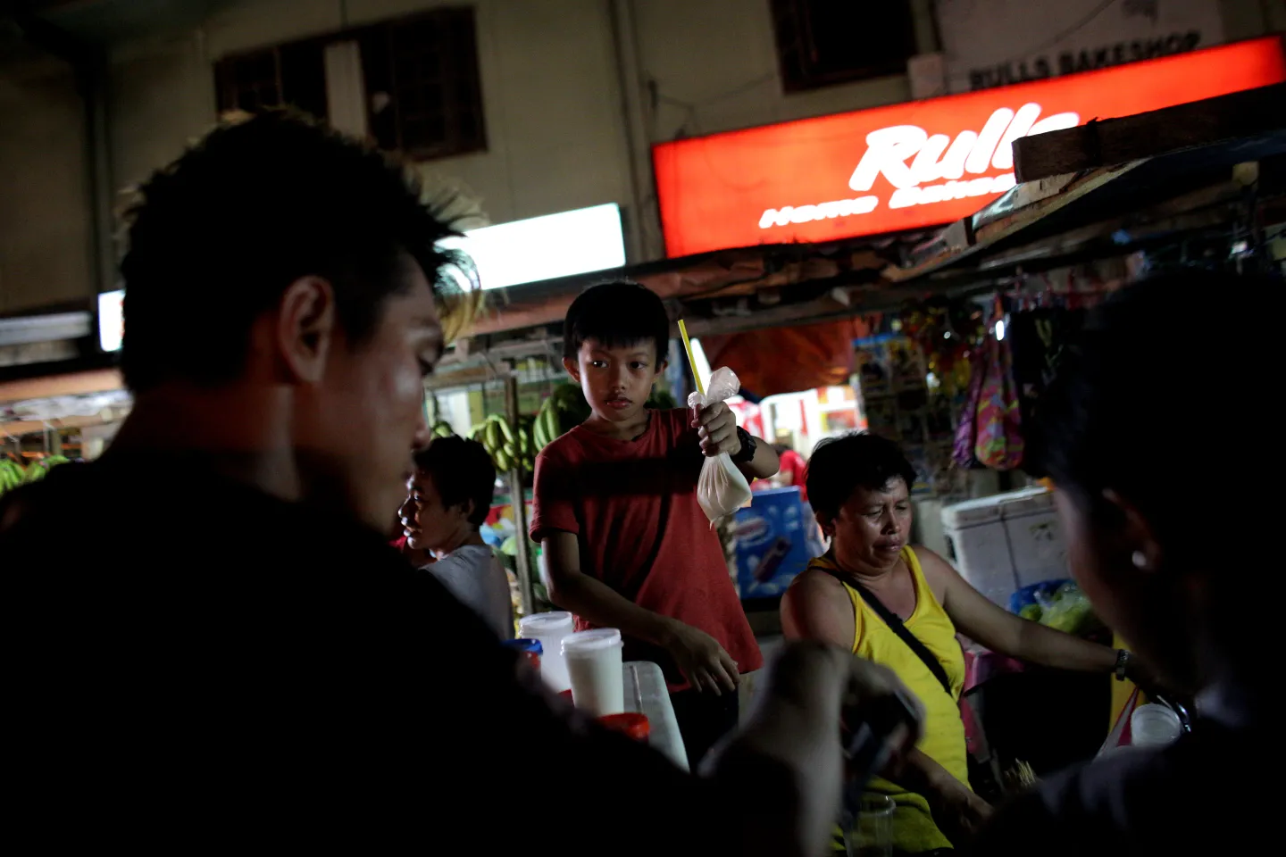 A boy holding a plastic bag contaning a drink