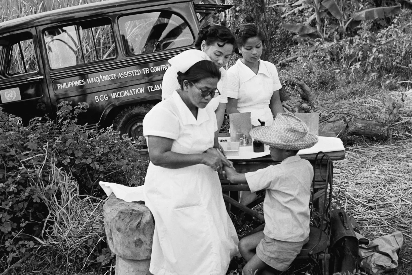 Nurses from a BCG vaccination team tests a boy for tuberculosis, at a table set up near a tree where their truck is parked, in the province of Batangas. 1956.