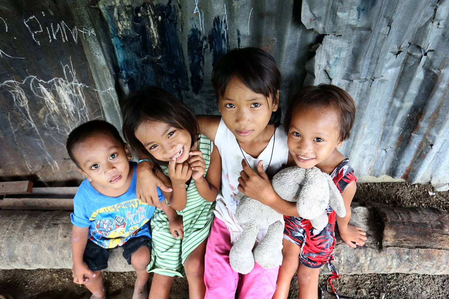 Four children sit outside their house