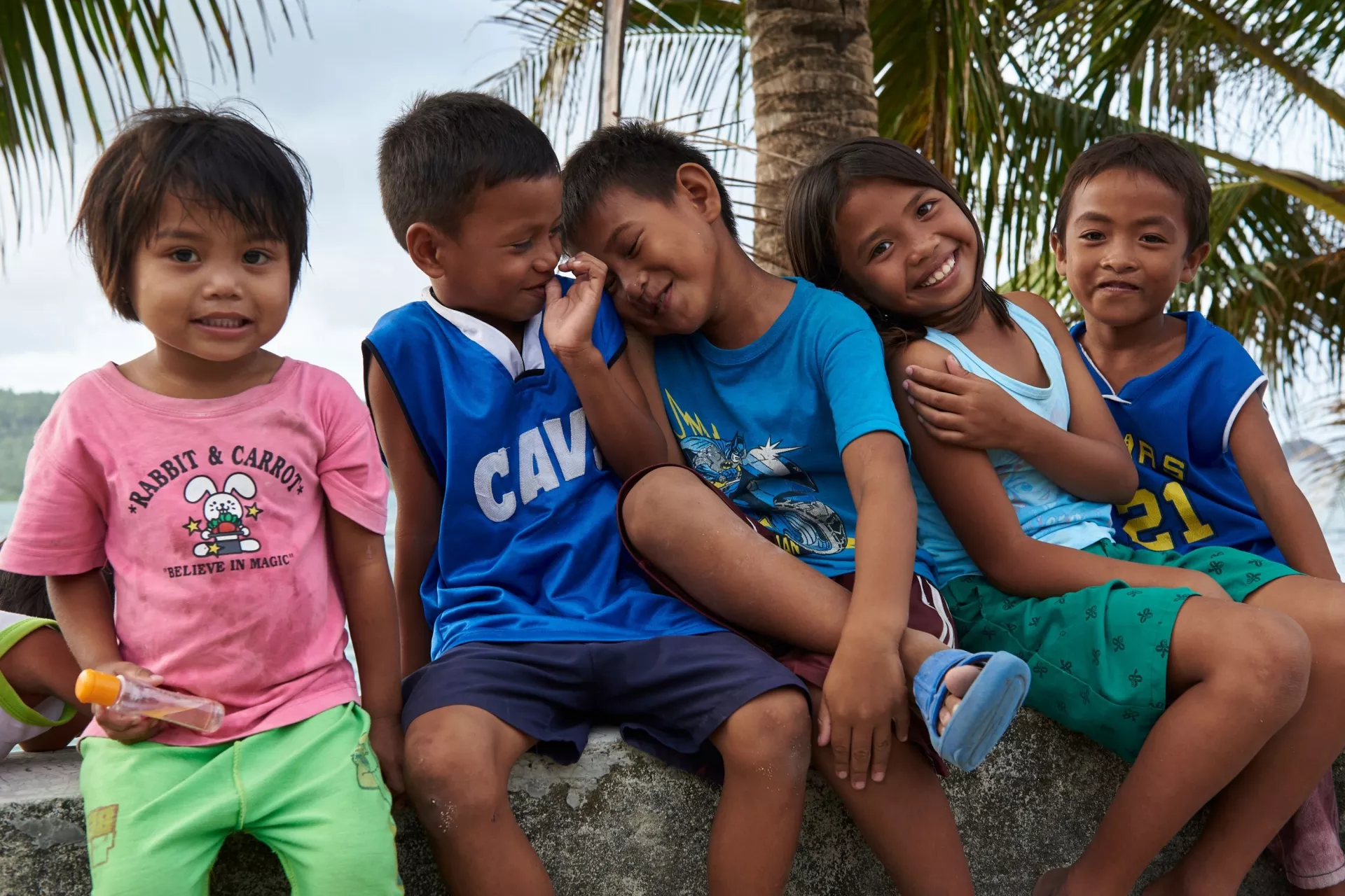 Children sitting on a ledge, smiling