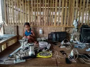 A child sitting amid cables, appliances and power outlets