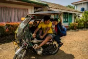 Baniamen fetches three of his children from school using his tricycle, which he also uses for work.