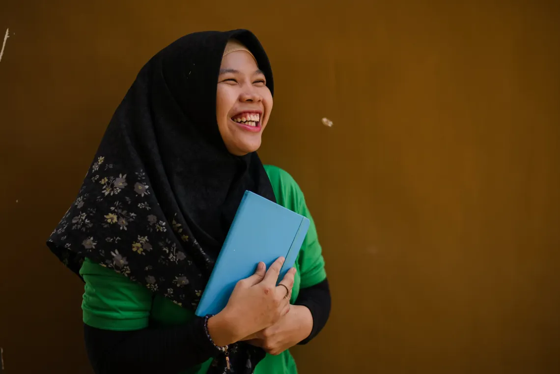 Anida, a young person with physcial disability, holds the notebook