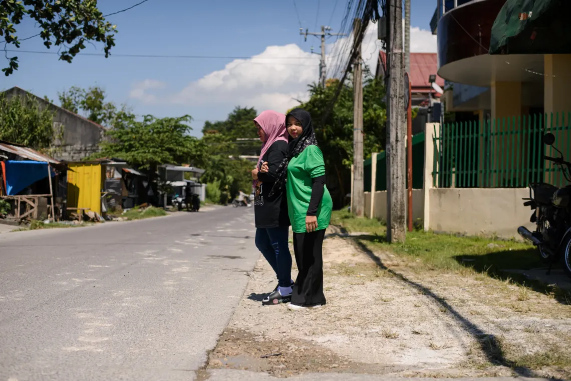 Anida, a young person with physical disability, crosses the street with her sister