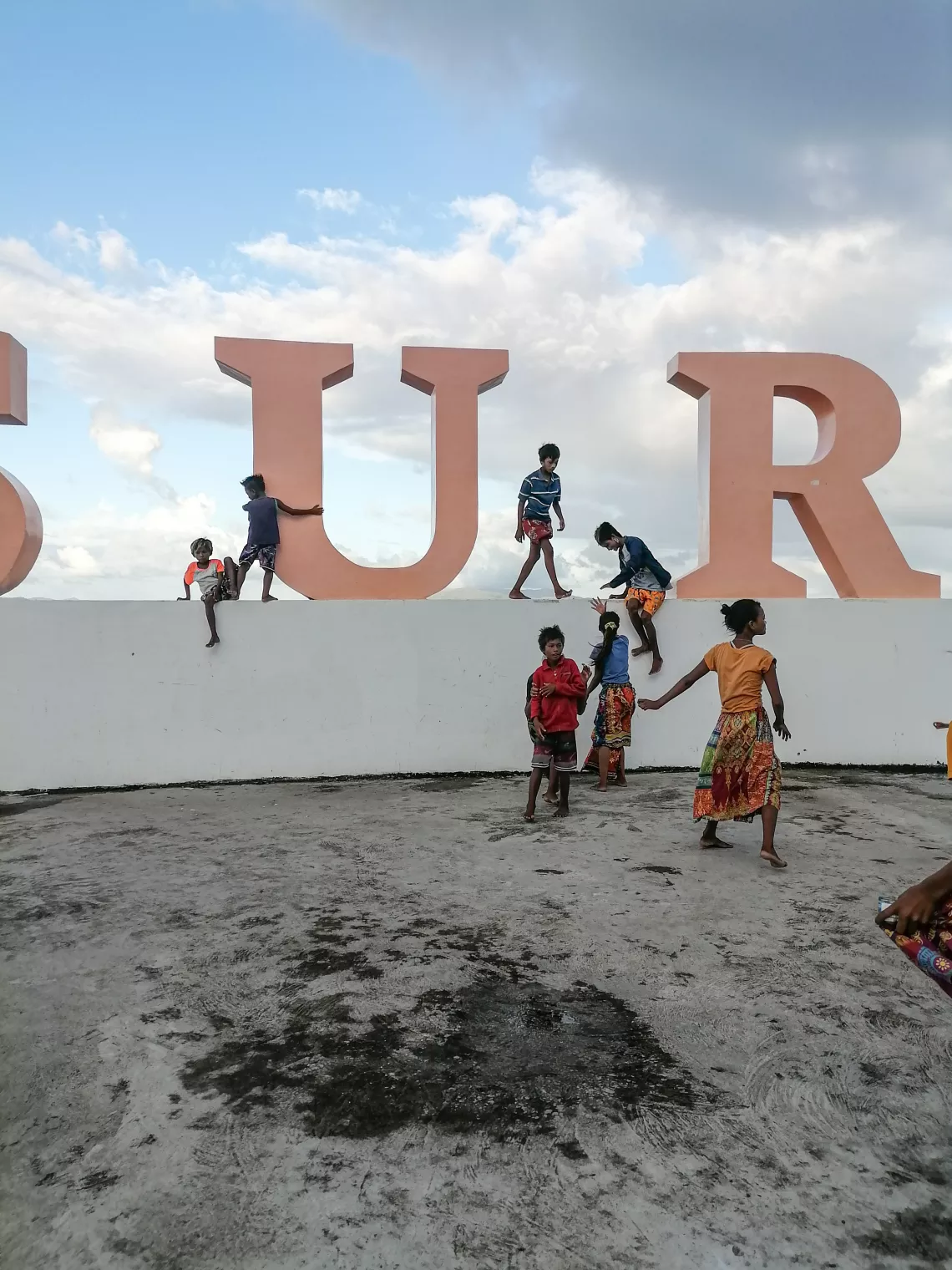 Children playing by giant letters at a boardwalk