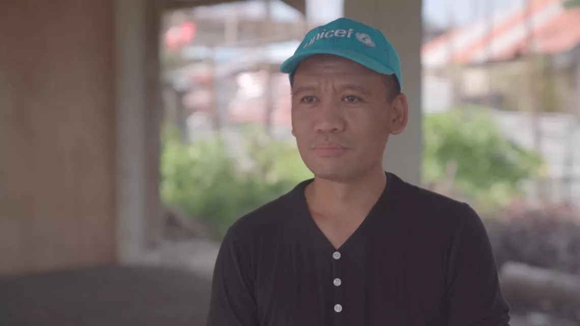 A UNICEF staff member wearing a cyan hat with the UNICEF logo