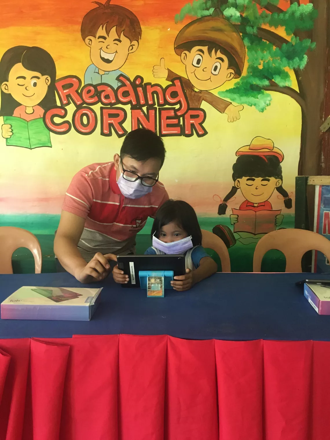 A teacher instructs a learner using a tablet device
