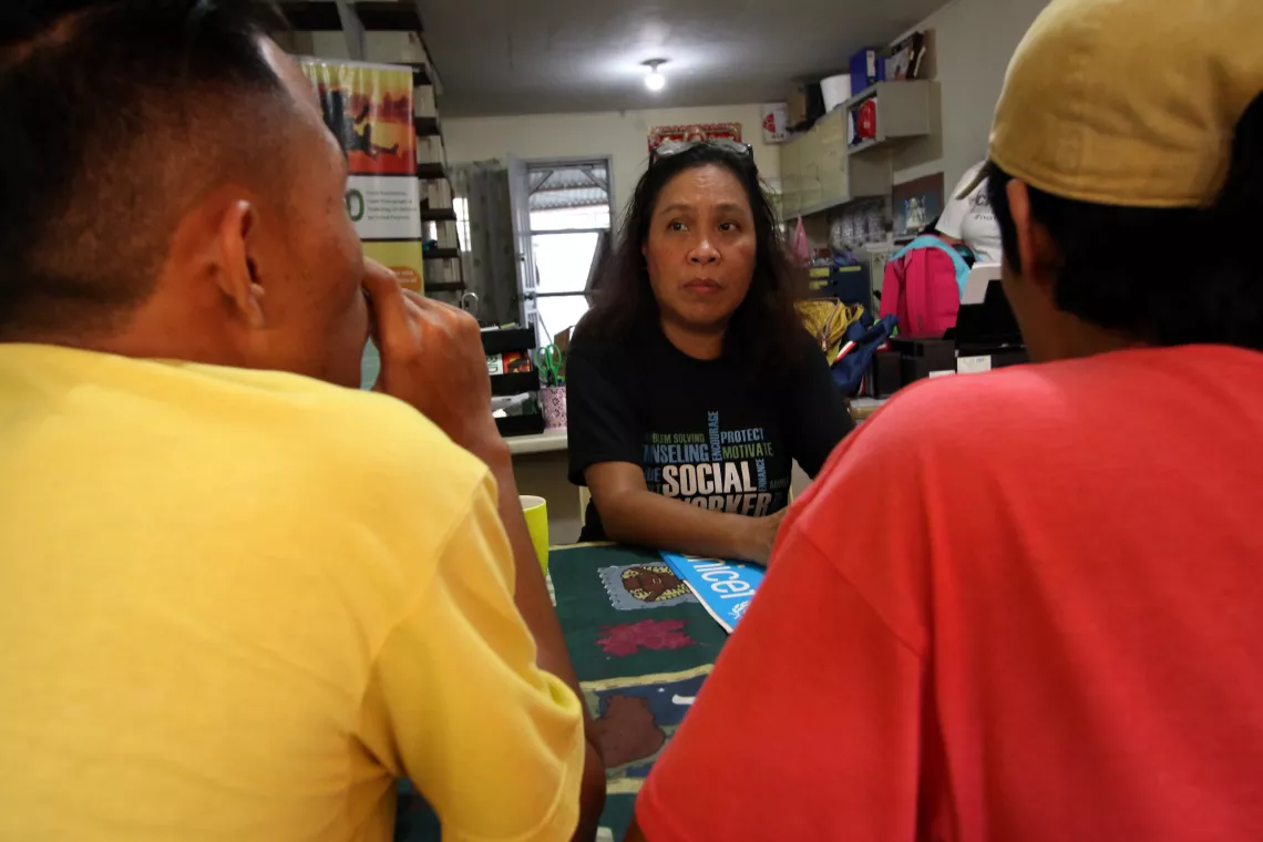 Two boys, facing away from the camera, talking to a social worker