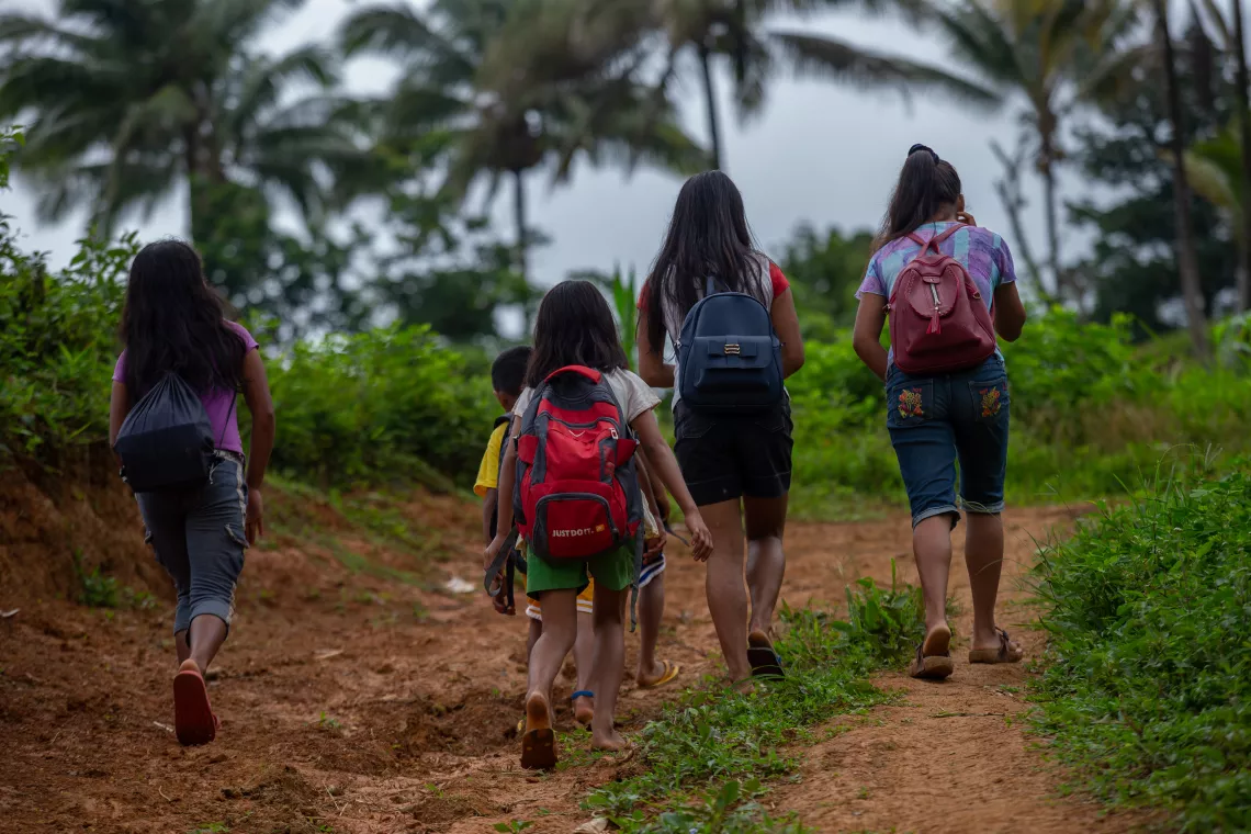A group of children walk to school carrying backpacks