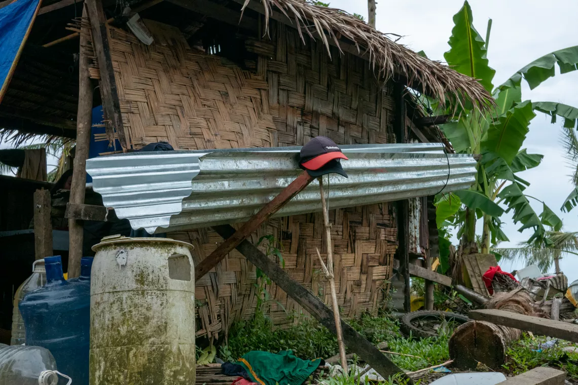 A makeshift rain harvesting setup using the thatched roof and corrugated metal as a gutter