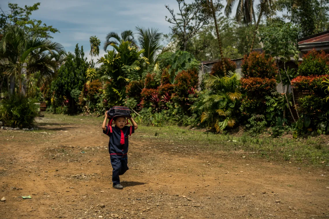 Alnur, 4, carrying his bag as he arrives at school.
