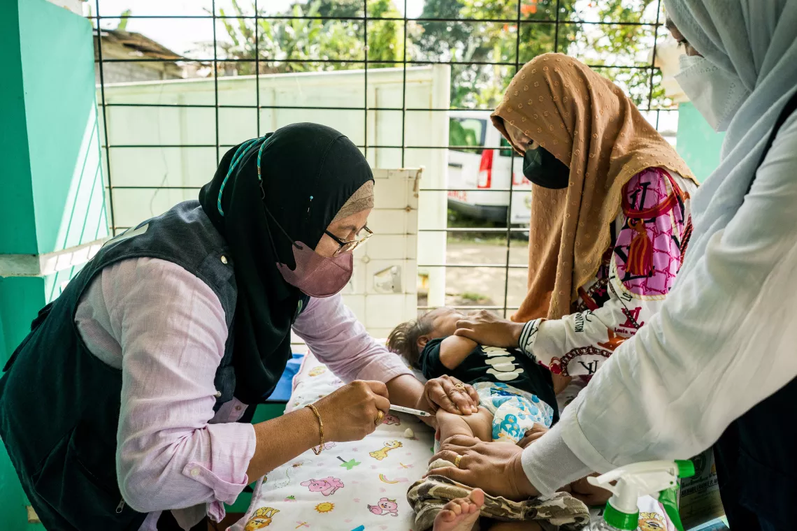 A midwife administers a routine vaccine to a child