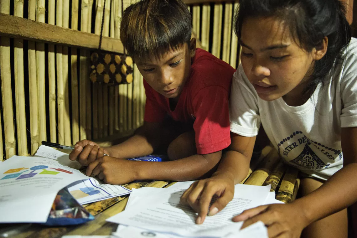 Siblings studying at home using printed learning modules