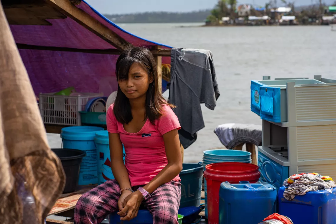 A girl sitting by a makeshift shelter by the sea