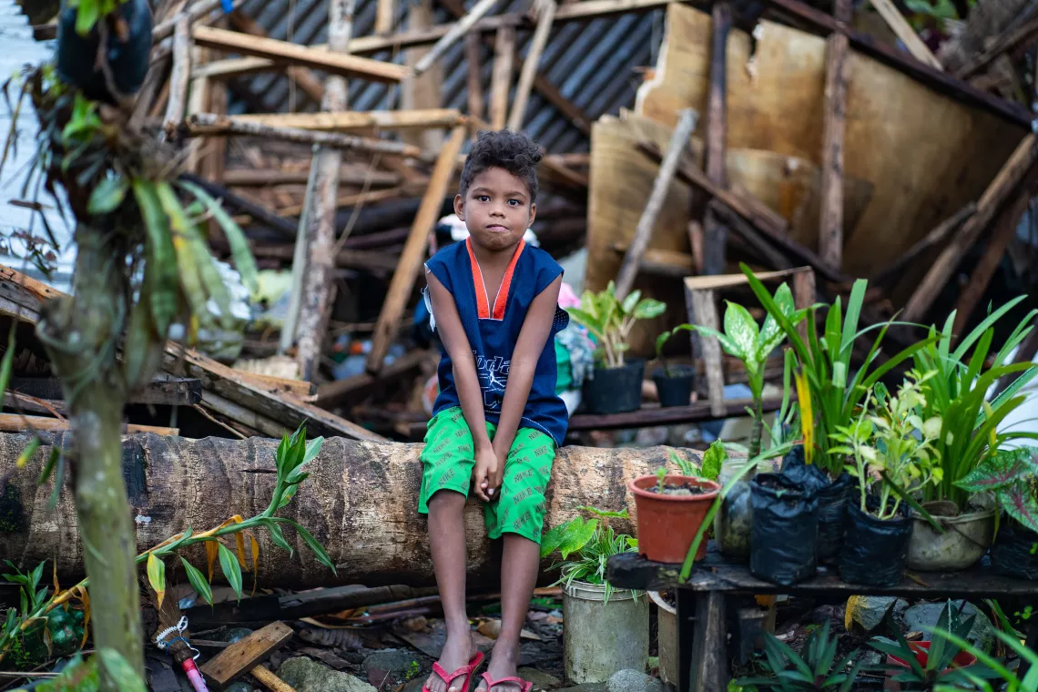 A child sitting on debris of a destroyed home