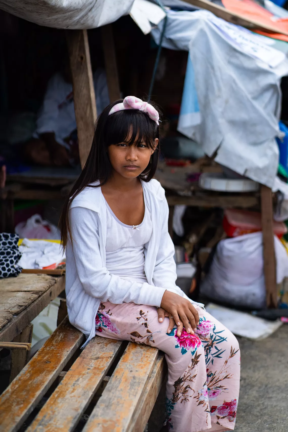 A girl sitting by their house damaged by a typhoon