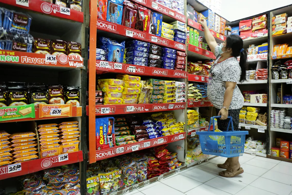 A customer stands on her toes as she reaches out to get a biscuit from the top shelf.