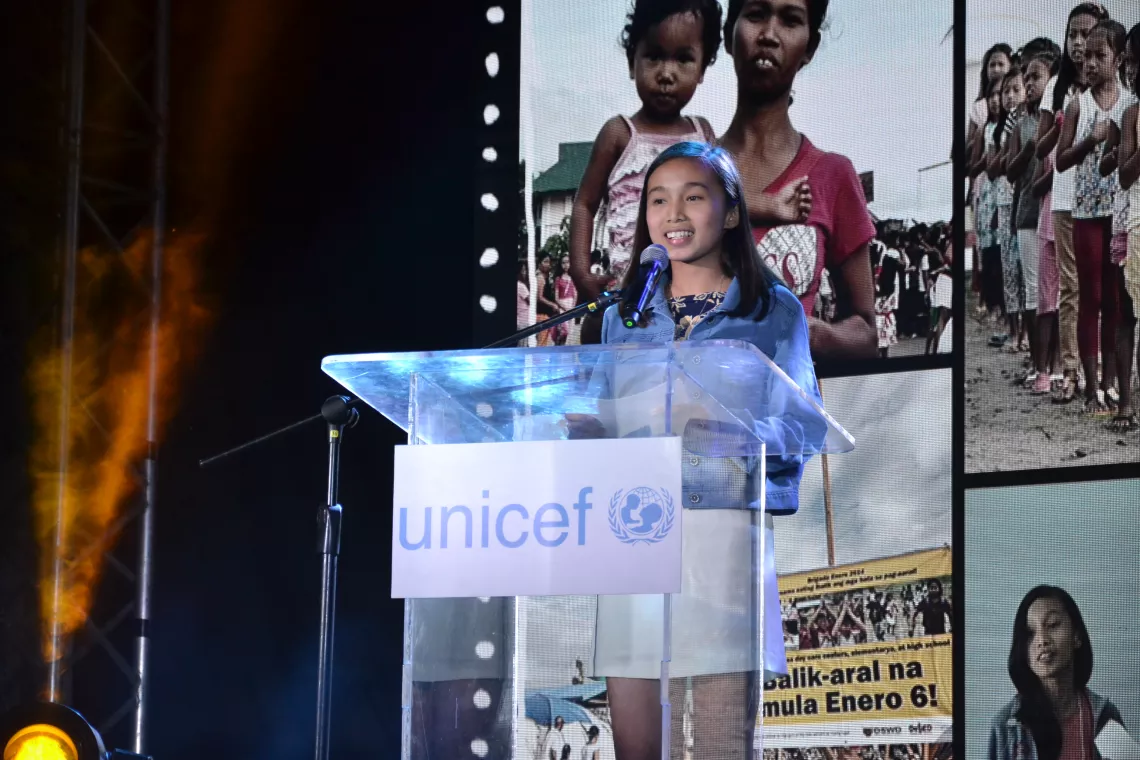 Kiana Gualberto stands onstage to deliver a speech