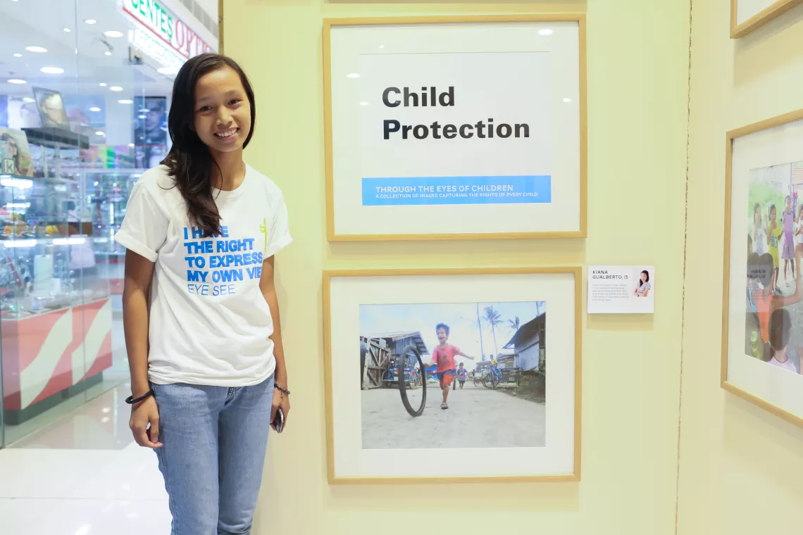 Kiana Gualberto stands beside a framed print of a photo she took as part of UNICEF's Eye-See photography workshop