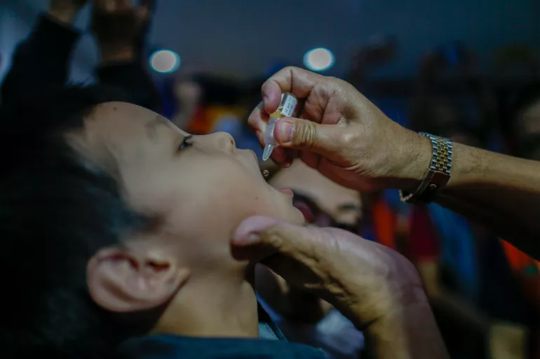A child receives a dose of oral polio vaccine
