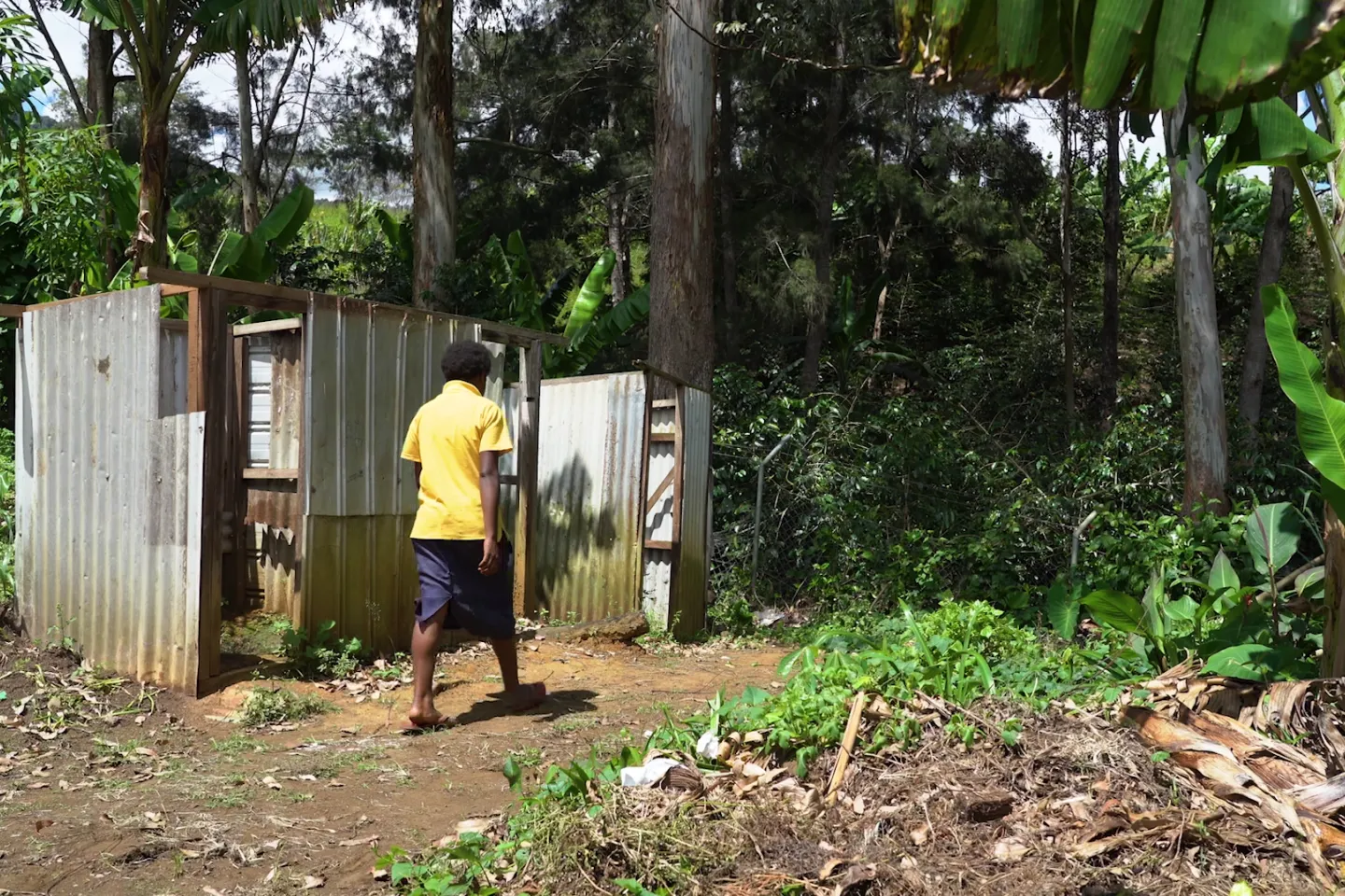 Female student walking towards a dilapidated toilet