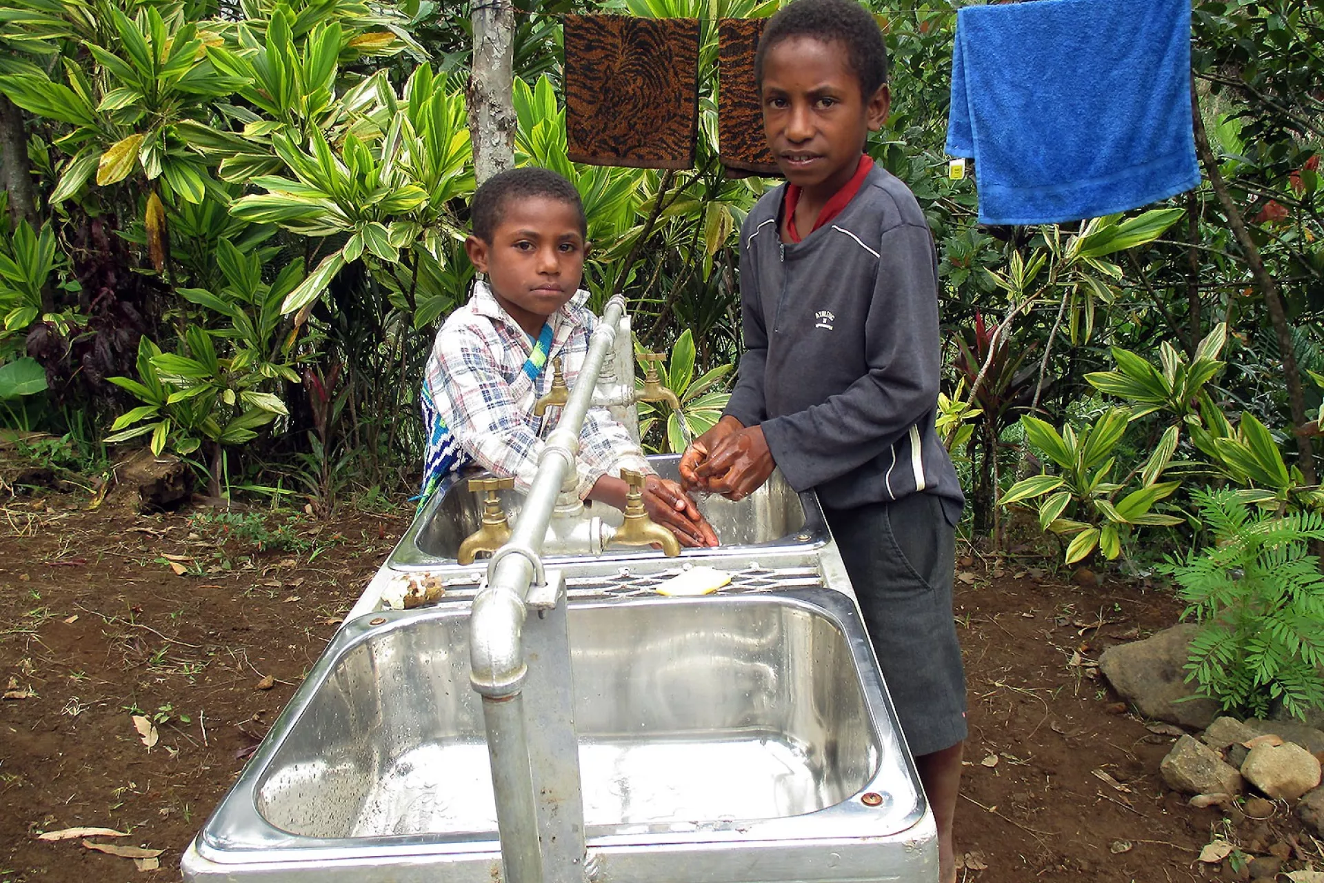 Japhet and his friend wash their hands after playing