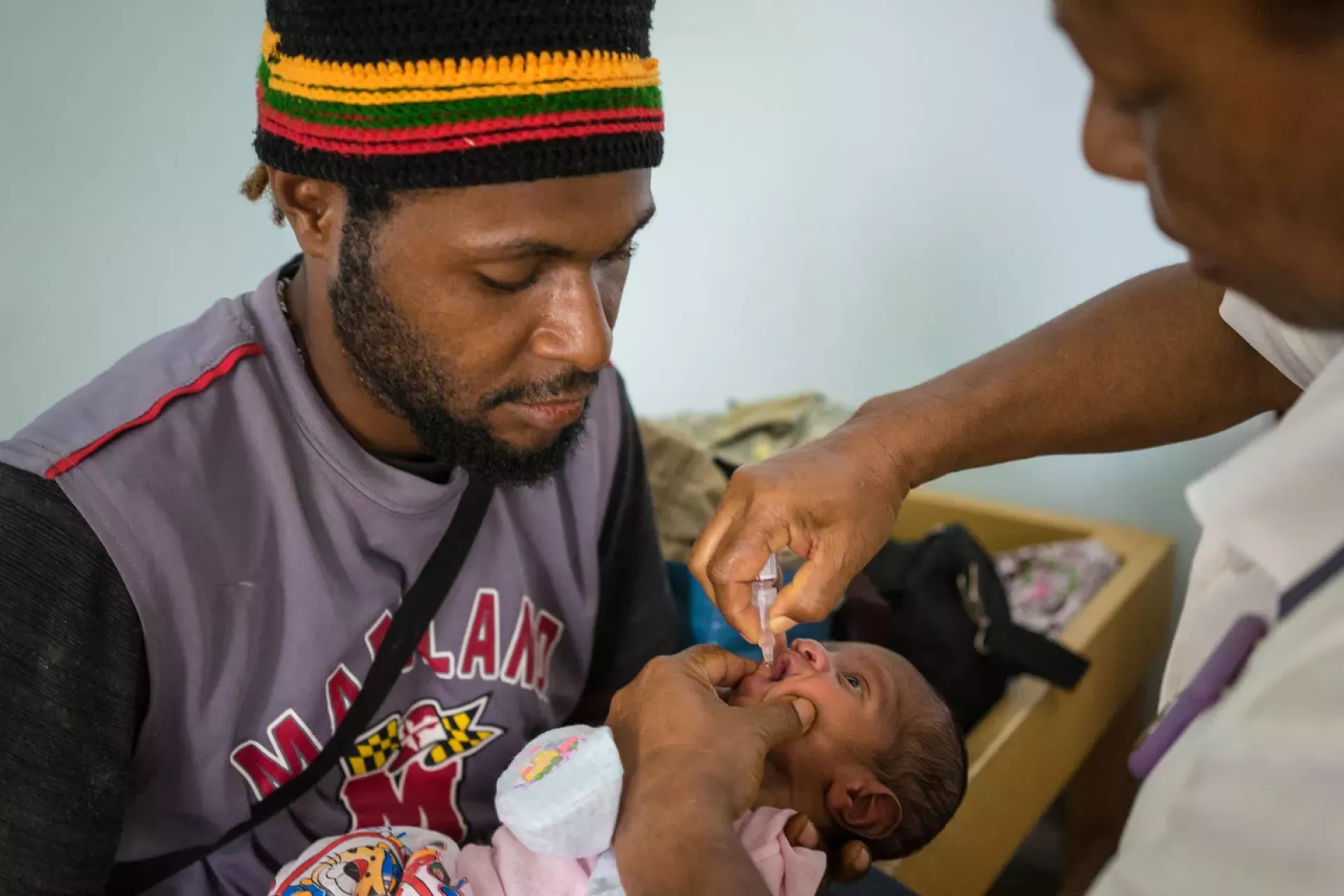 A nurse administers polio drops to a newborn baby at the Modilon Hospital in Madang Povince while the baby's father looks on.