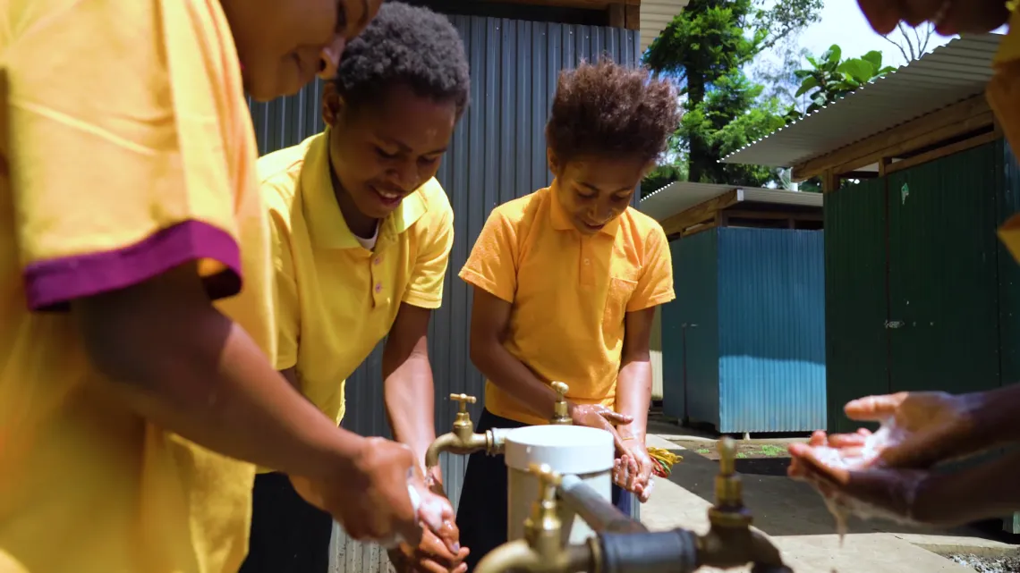 Girls washing hands beside their new toilets.