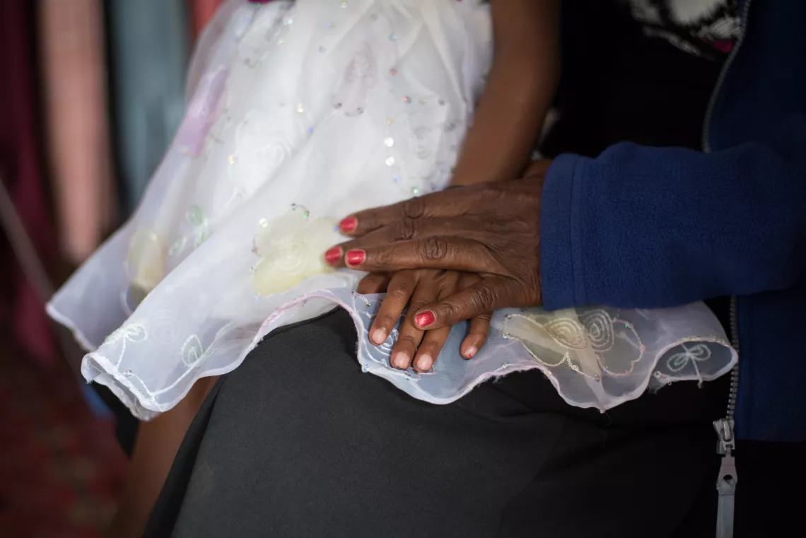 A mother holding her baby's hands.