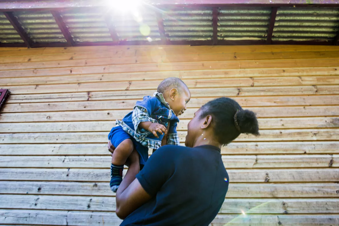 A mother holding her baby up in the air.