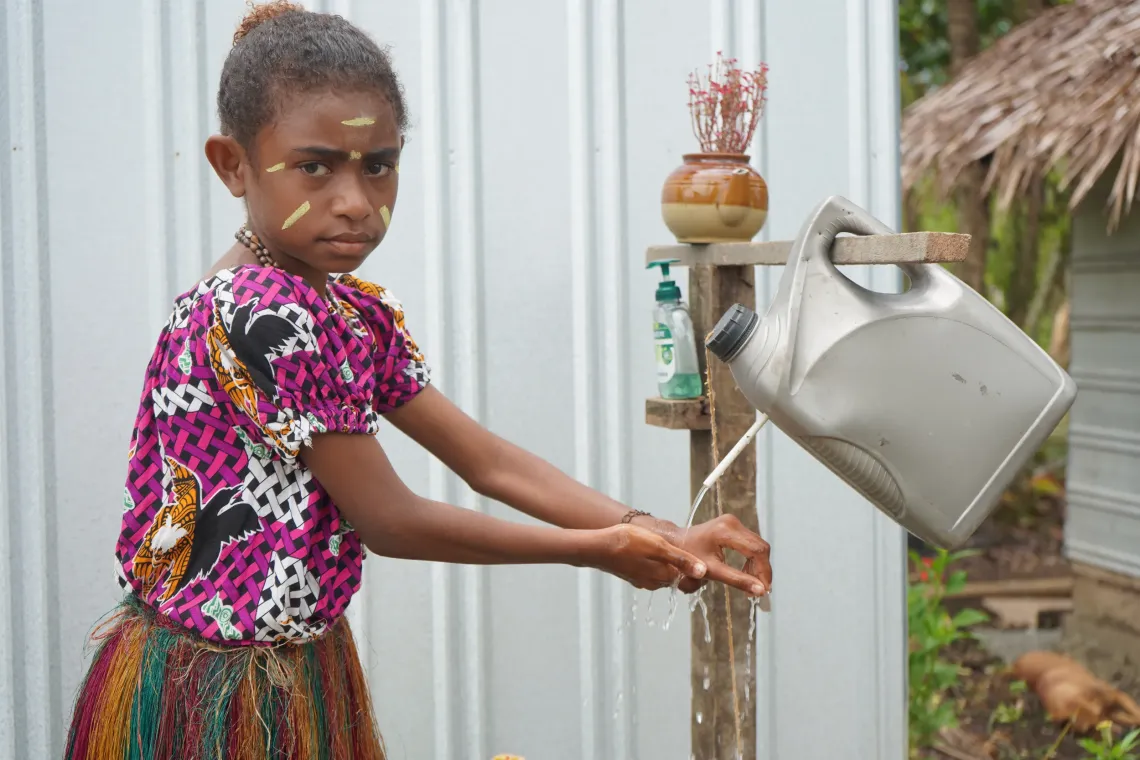Gideon's daughter, Aileen, shows off the tippy tap her father installed to ensure they wash their hands after using the toilet.