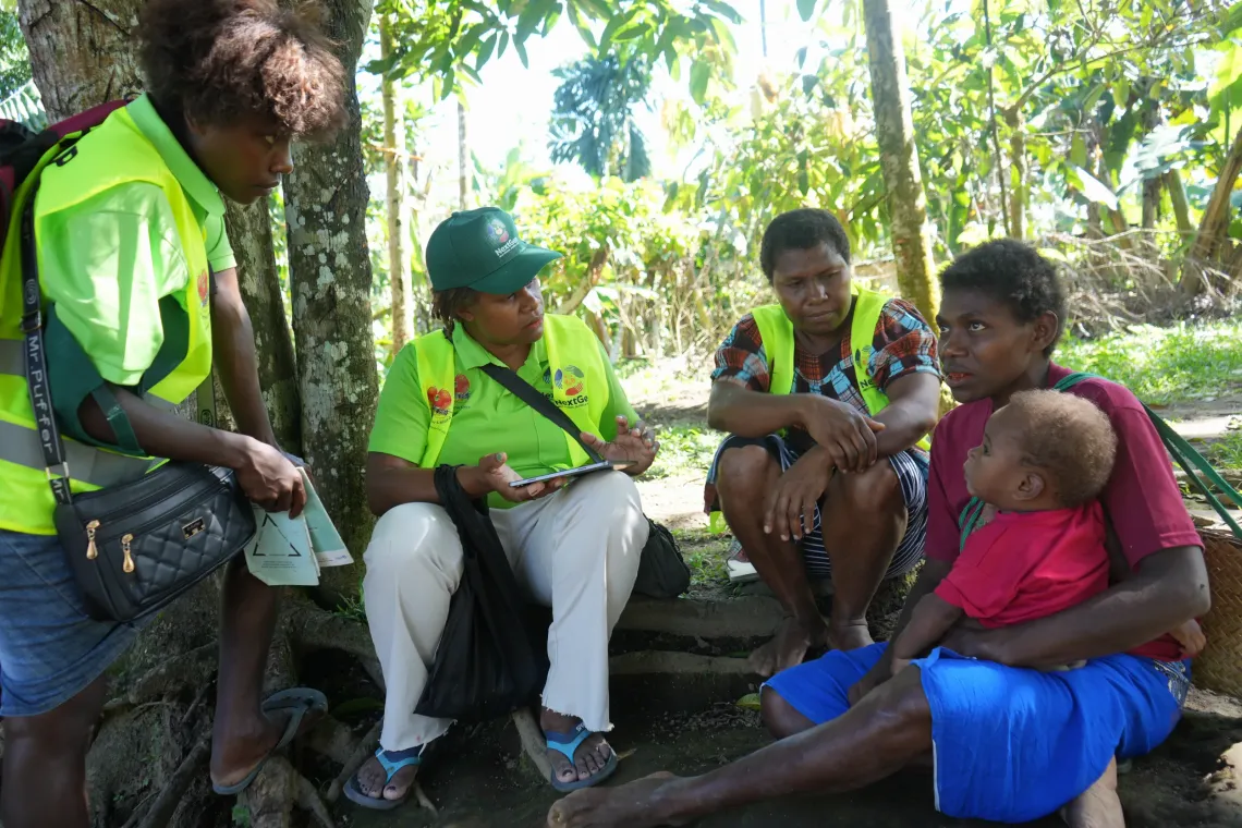 Nursing Officer, Dorothy, (second from left) helps collect information from a mother.