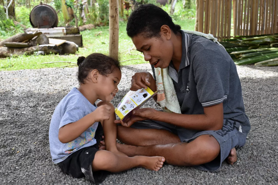 A mother helping her child to read a book.