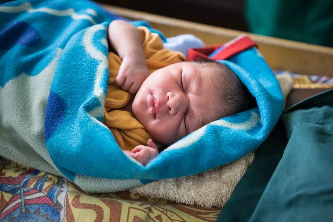 A newborn baby sleeping in a hospital facility.