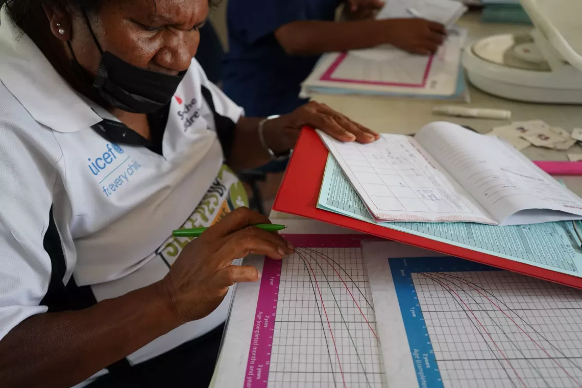 Sr. Hombunaka Sr. Hombunaka refers to weight charts to help enter correct details in the child health record book.