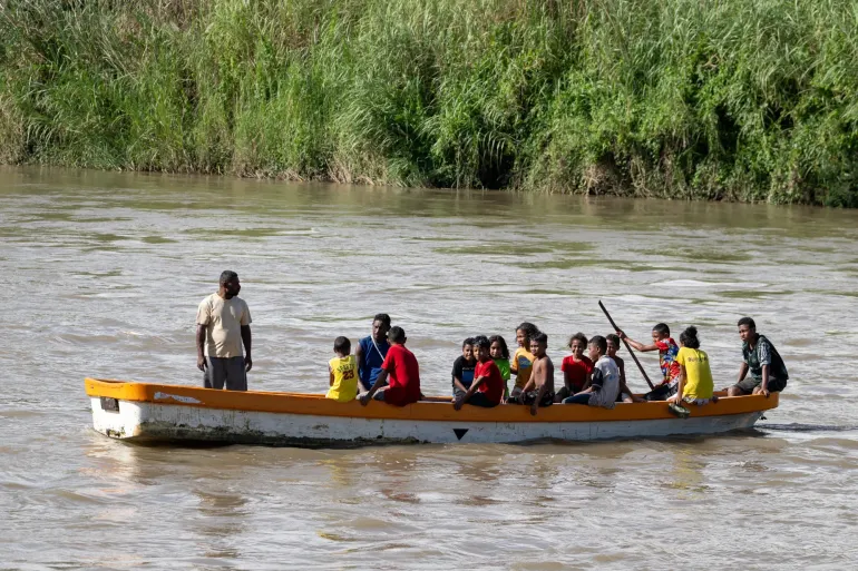 Younger children, safely seated in a small dinghy, cross the river after school.