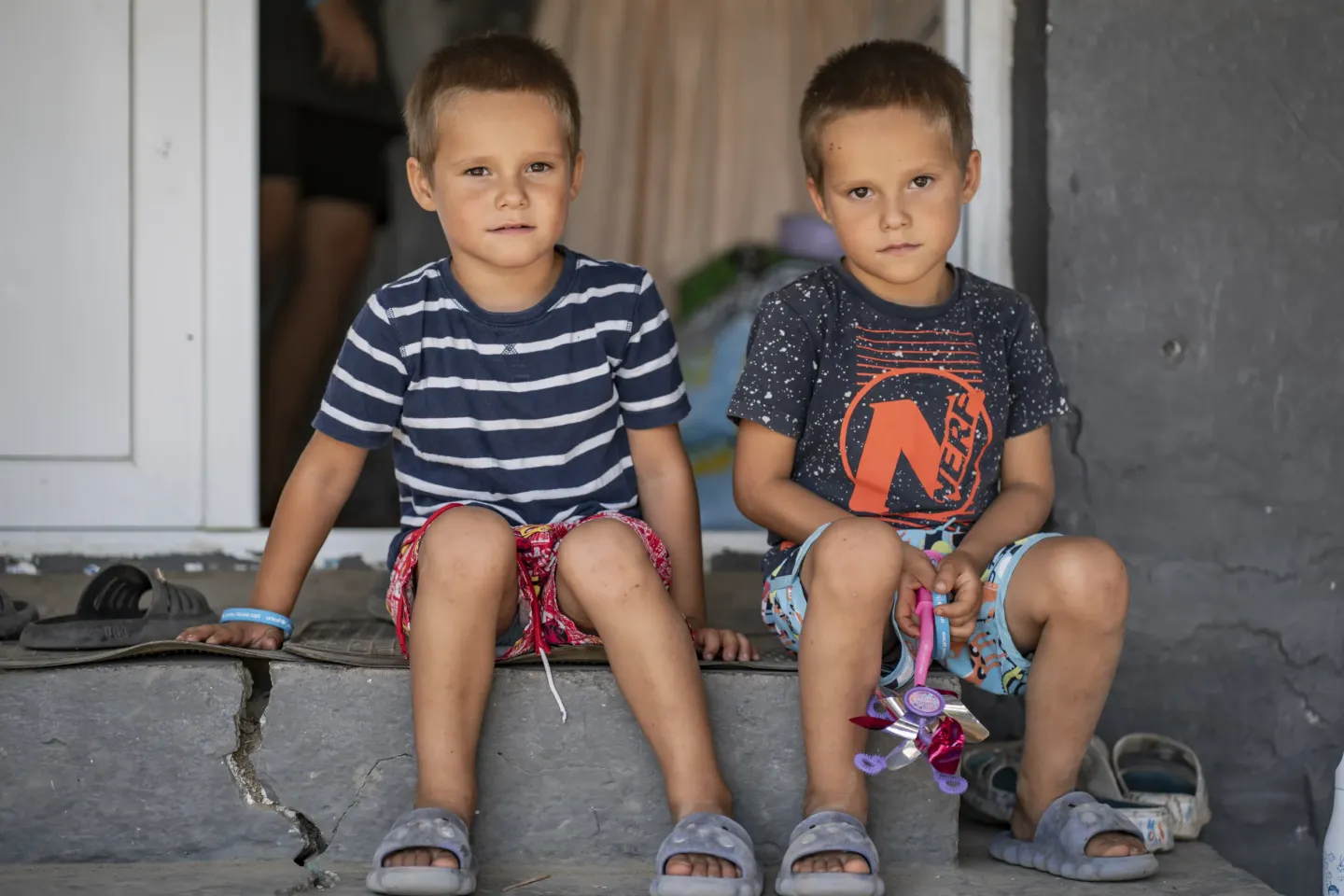 Twins sitting in front of their house