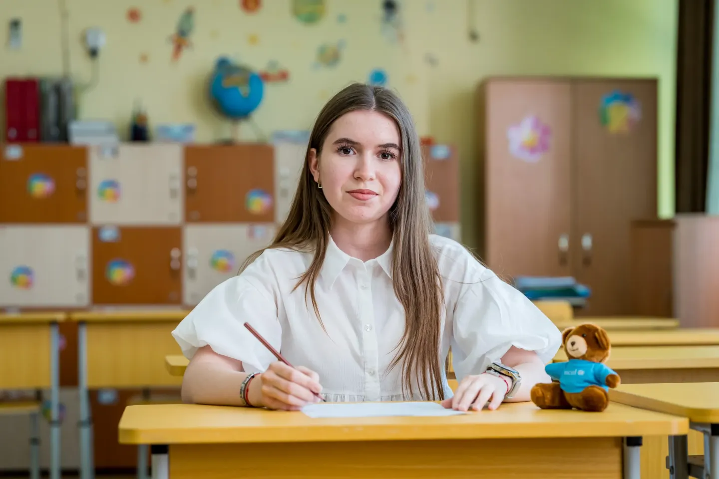 Portret cu o elevă care stă &icirc;n bancă, &icirc;ntr-o sală de clasă.