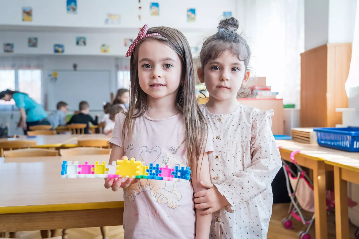 Doi copii pozează pentru o fotografie &icirc;ntr-o sală de clasă dintr-o grădiniță din Brașov, Rom&acirc;nia.