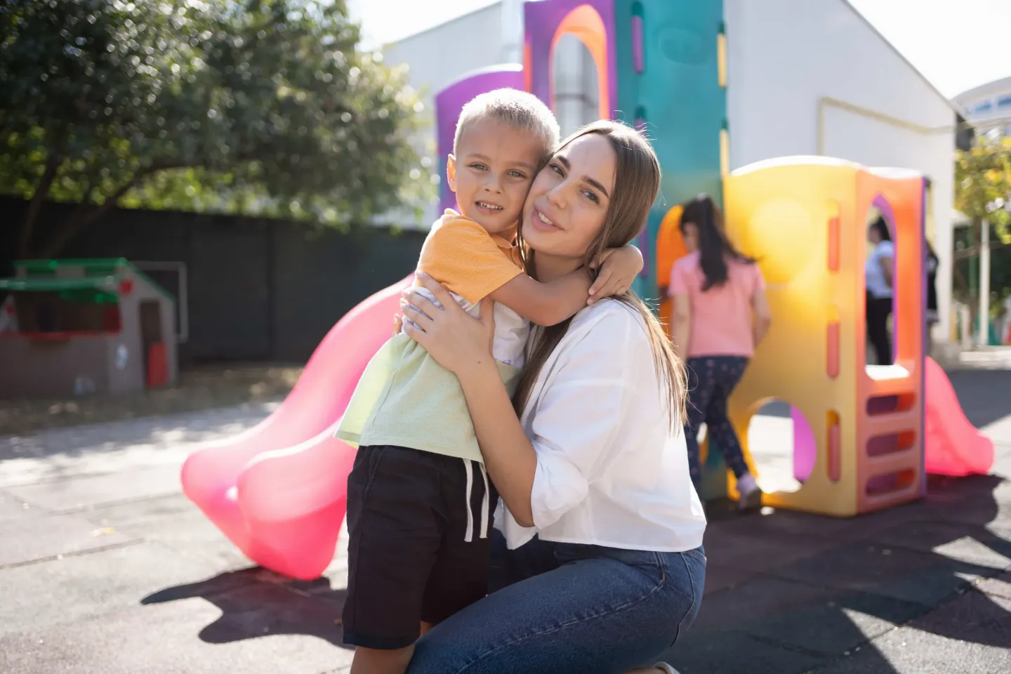 Mom and child hugging each other outside in the playground.