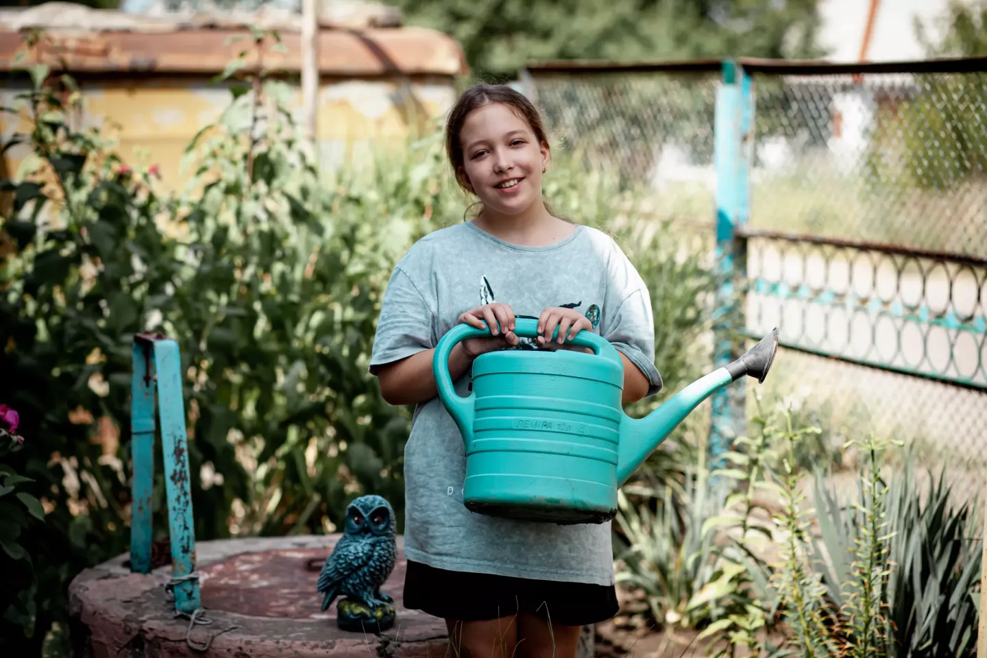 Ten-year-old Polina waters flowers in her family&rsquo;s garden in Velyka Oleksandrivka.