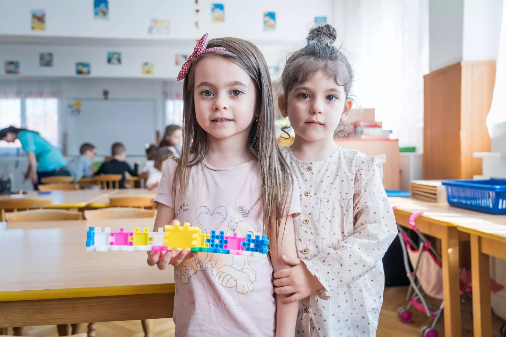 Doi copii pozează pentru o fotografie &icirc;ntr-o sală de clasă dintr-o grădiniță din Brașov, Rom&acirc;nia.