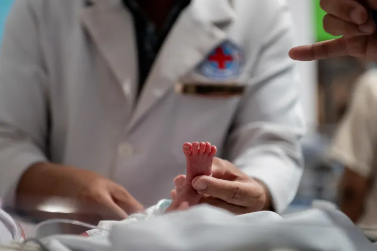 a doctor examines the tiny foot of a premature newborn