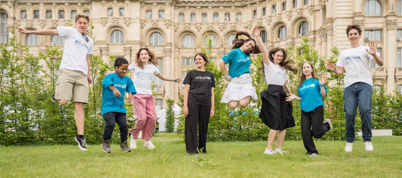 Grup de copii afară, sărind &icirc;n aer de fericire. 