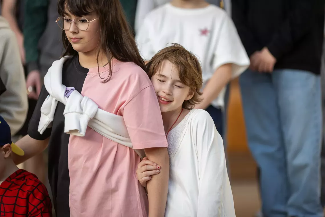 O adolescentă &icirc;mbrățiș&acirc;nd brațul prietenei sale.