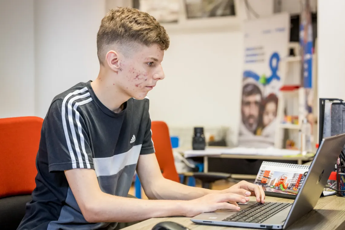 Un adolescent navig&acirc;nd pe laptop.