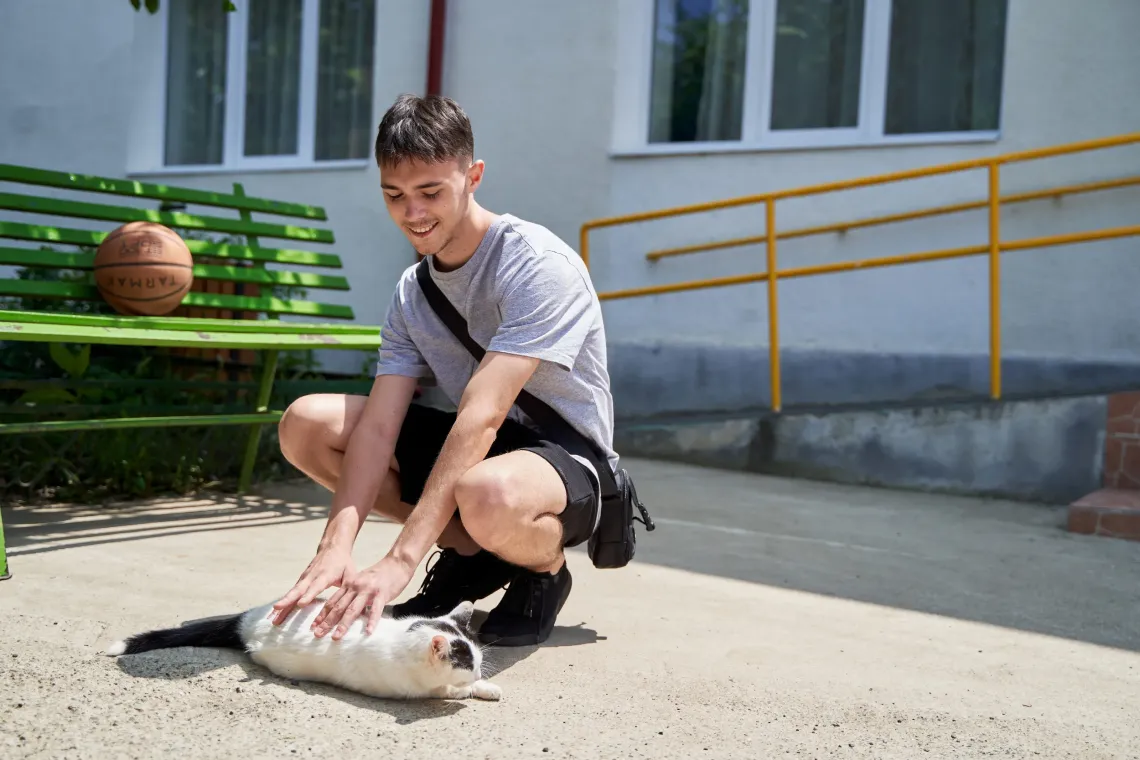 Young boy playing outside with a cat.