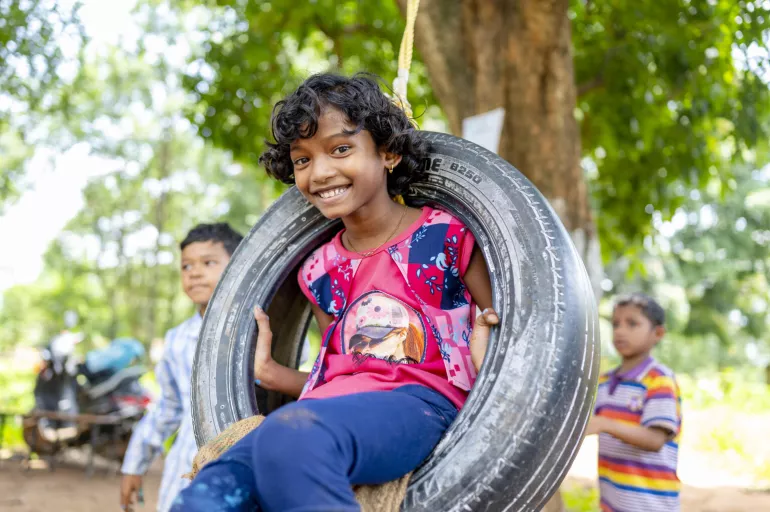 A child is using a swing made of a car tyre