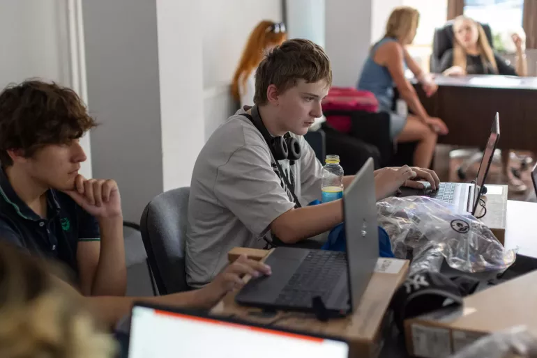 Adolescents in class, working on laptops