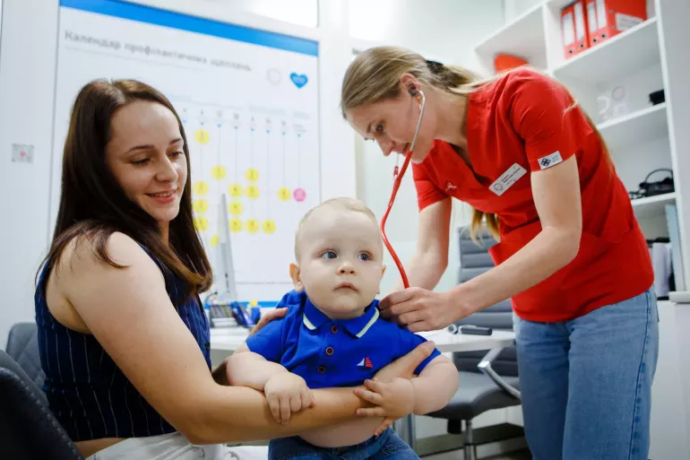 Mother holding her son during consultation before vaccination.